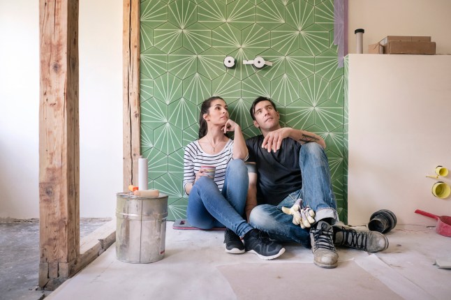 Couple renovating new house, sitting on ground planning bathroom